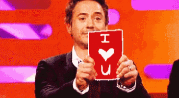 a man in a suit is holding a card that says i love you .