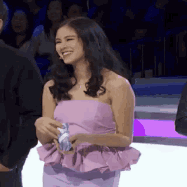 a woman in a pink dress is smiling while holding a napkin in her hand .