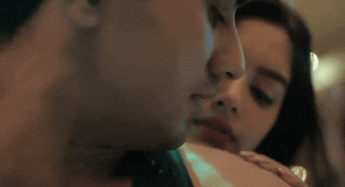 a close up of a man and woman kissing each other .