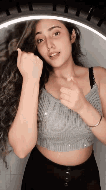 a woman in a gray crop top and black shorts is standing in front of a mirror