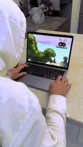 a person is typing on a laptop with a gameboy logo on the screen