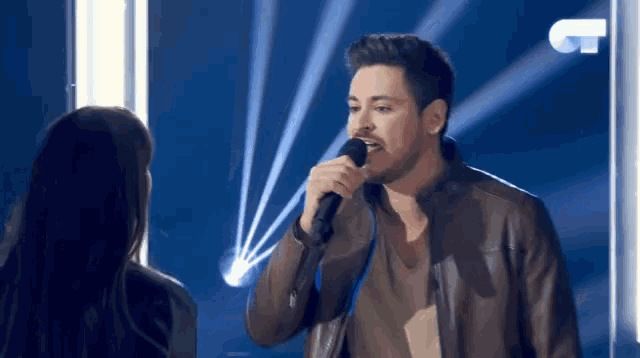 a man singing into a microphone in front of a woman