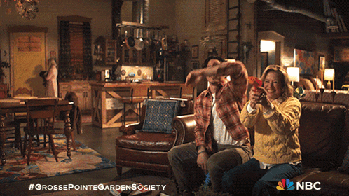 a man and woman are sitting on a couch playing a video game with nbc written on the bottom
