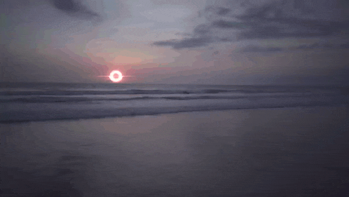 a person standing in the ocean with a black hole in the sky behind them
