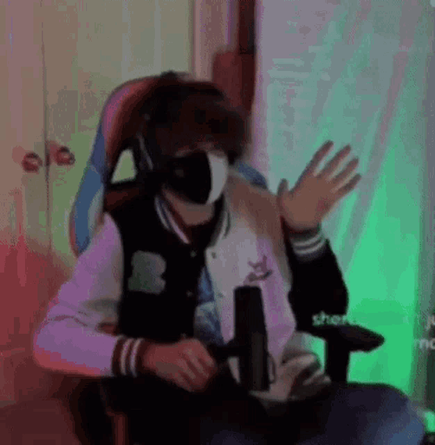 a person wearing a mask and headphones is sitting in a chair .