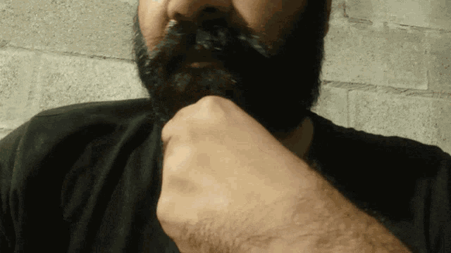 a man with a beard has his hand on his face