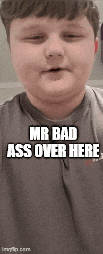 a young boy is wearing a gray shirt that says " mr bad ass over here "