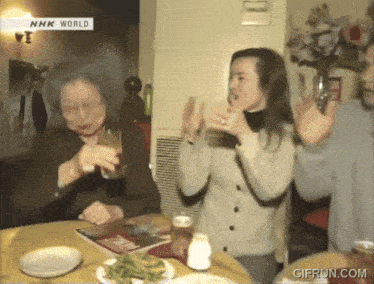 a woman sitting at a table with plates and a sign that says nhk world on it