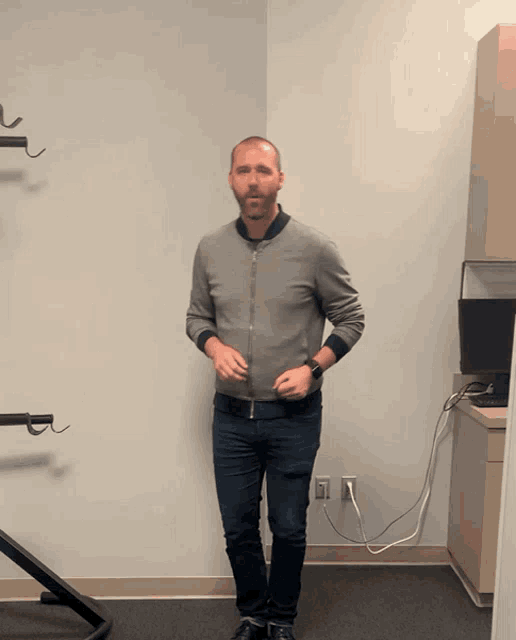 a man in a grey jacket stands in a corner of an office