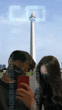 a man and a woman are taking a selfie in front of a tower