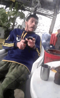 a man in a blue shirt with the letter u on it is sitting in a chair