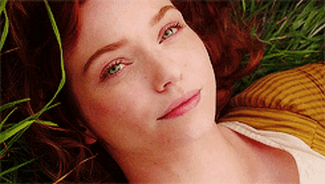 a woman with red hair is laying in the grass