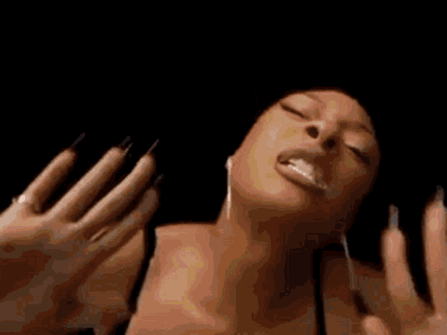 a woman in a black bra and earrings is making a funny face in a dark room .