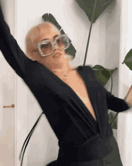 a woman wearing a black bodysuit and sunglasses is dancing