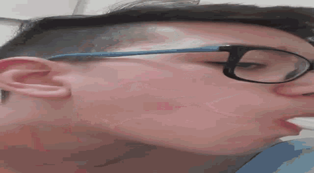a close up of a person 's face with glasses and a napkin in their mouth .