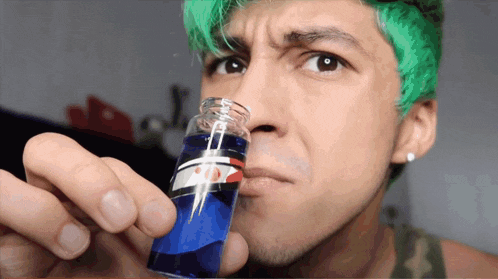 a man with green hair is holding a blue bottle
