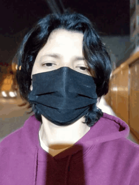 a man wearing a black mask and a purple hoodie