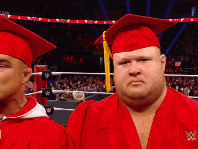 a man wearing a red graduation cap and gown with a w logo on his shirt