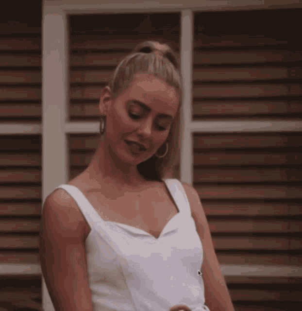 a woman in a white tank top and hoop earrings