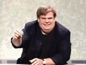 a fat man in a suit and black shirt is sitting at a table making a funny face .