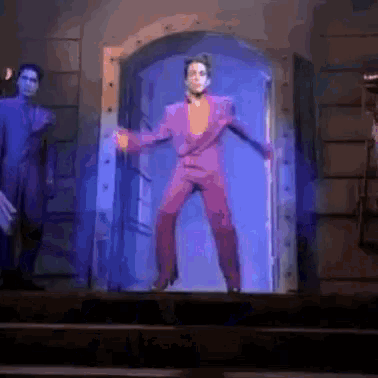 a man in a purple suit is dancing in a doorway