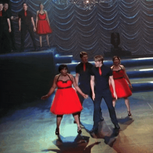 a woman in a red dress is dancing with a man
