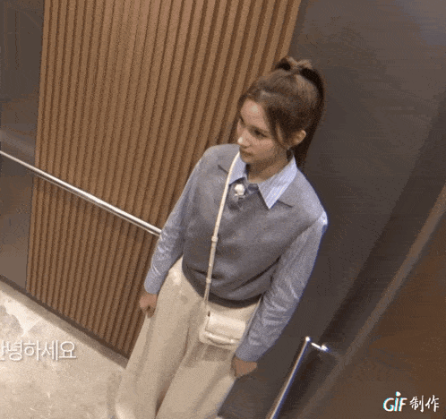 a woman standing in an elevator with gif written on the bottom right