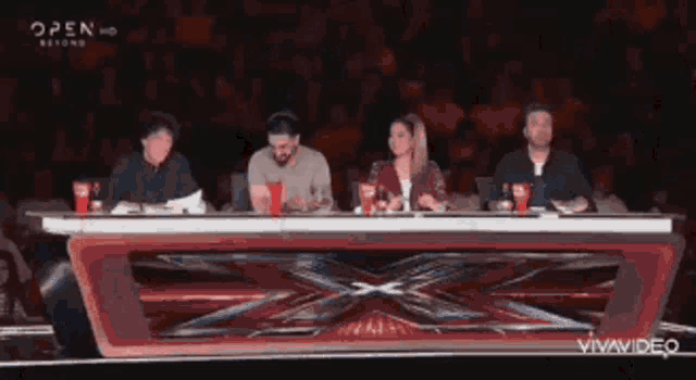 a group of people sitting at a table in front of a sign that says " open hd "