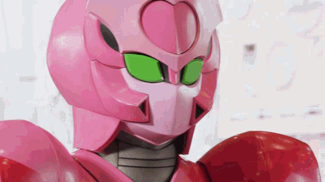 a pink robot with green eyes and a heart shaped helmet