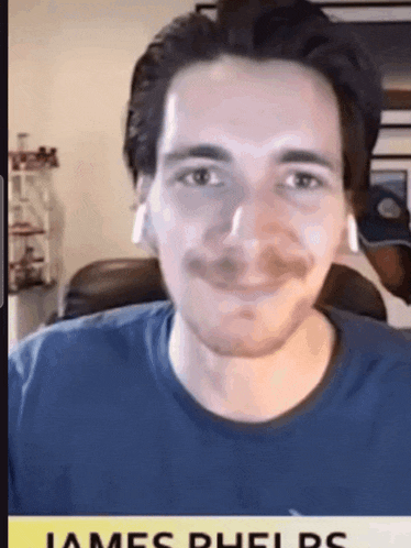 a man wearing ear buds and a blue shirt with the name james phelps on it