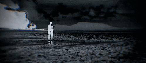 a black and white photo of a man fishing in the ocean