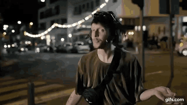 a man wearing headphones and a helmet is standing in the middle of a street at night .