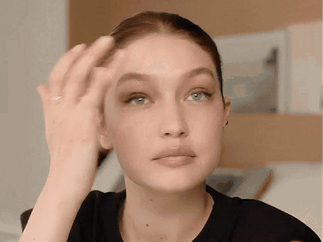 a close up of a woman 's face with a hand on her forehead