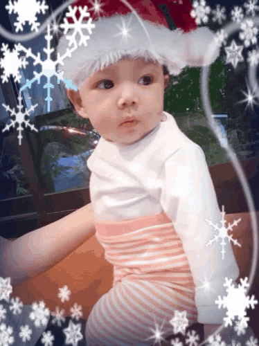 a baby wearing a santa hat with snowflakes around him