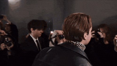 a group of people are taking pictures of a man in a suit