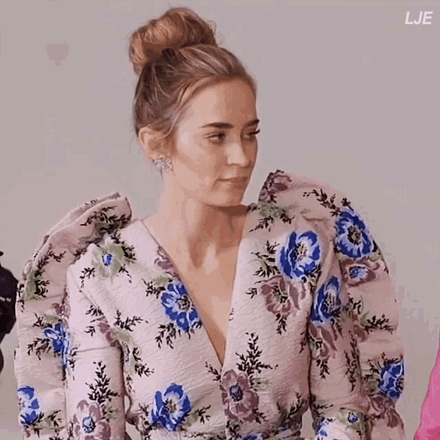 a woman is wearing a floral dress with puffed sleeves and a bun in her hair