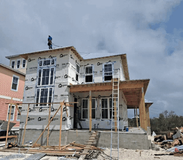 a house that is being built with a man on the top