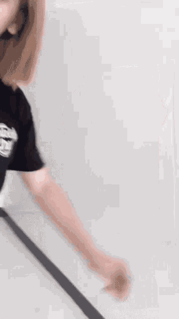 a woman wearing a black t-shirt is standing in front of a white wall .