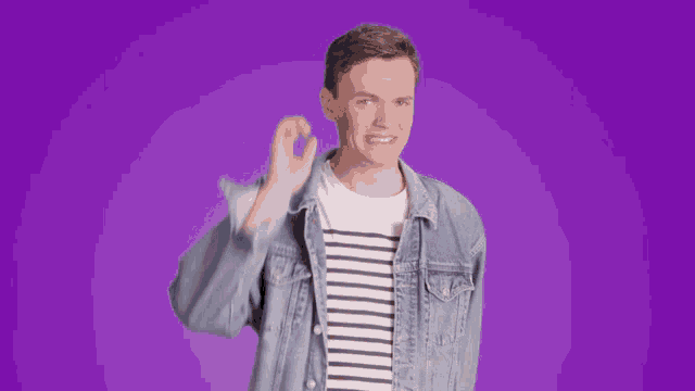 a man wearing a striped shirt and a denim jacket is giving the ok sign