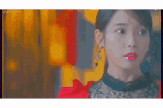 a close up of a woman 's face with a red lip and earrings .