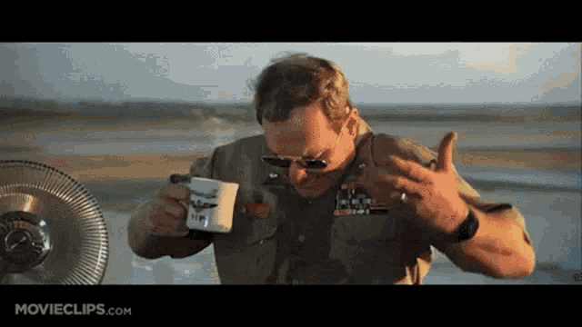 a man in a military uniform is drinking from a coffee mug that says nm on it