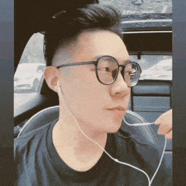 a man wearing glasses and ear buds looks to his left