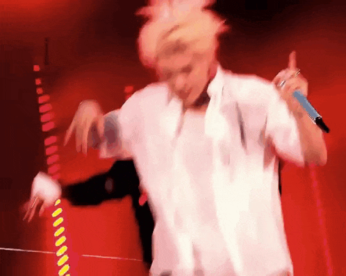 a man in a white shirt is holding a microphone and dancing .