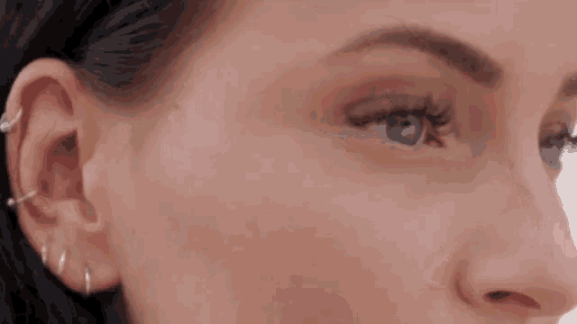 a close up of a woman 's face with earrings and a nose ring .