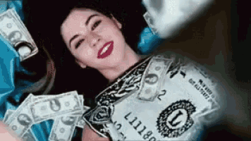 a woman is laying in a pile of money with a one dollar bill on her chest
