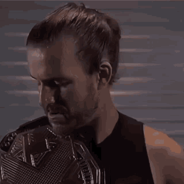 a man in a black tank top is holding a wrestling championship belt with the letter f on it