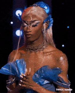 a woman wearing a blue dress and a necklace with the hashtag t4yce on the bottom right