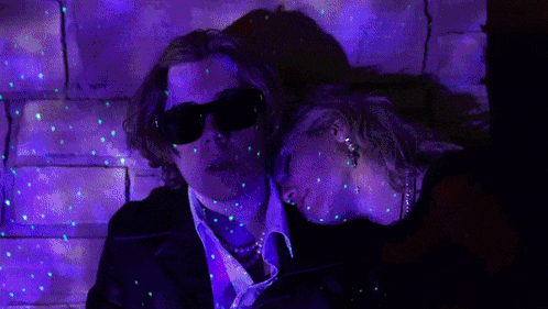 a man and a woman are hugging in a dark room with blue lights behind them