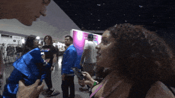 a woman with curly hair is talking to a man in front of a sign that says ' san diego ' on it