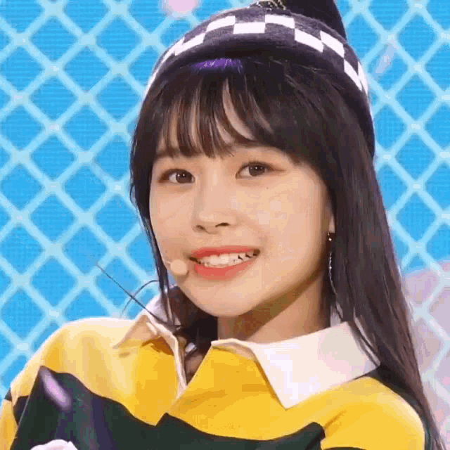 a close up of a girl wearing a yellow sweater and a hat with a microphone .